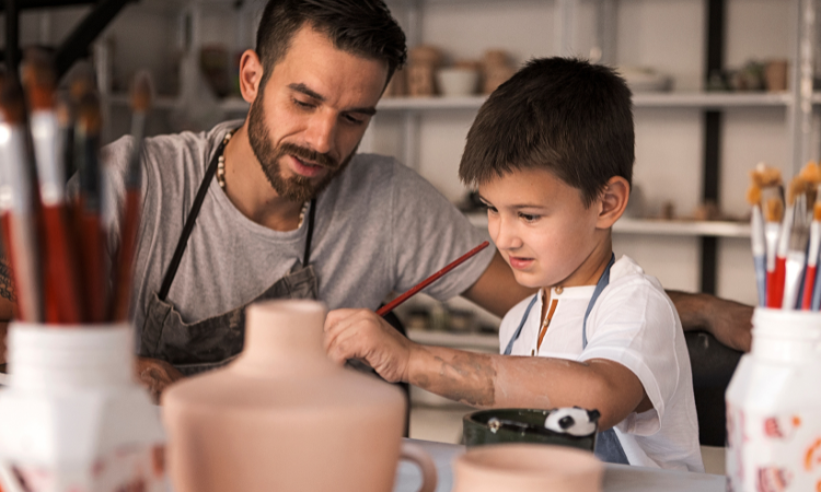 Man som lär barn att måla på keramik